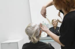 Senior woman getting haircut from female hairdresser in salon
