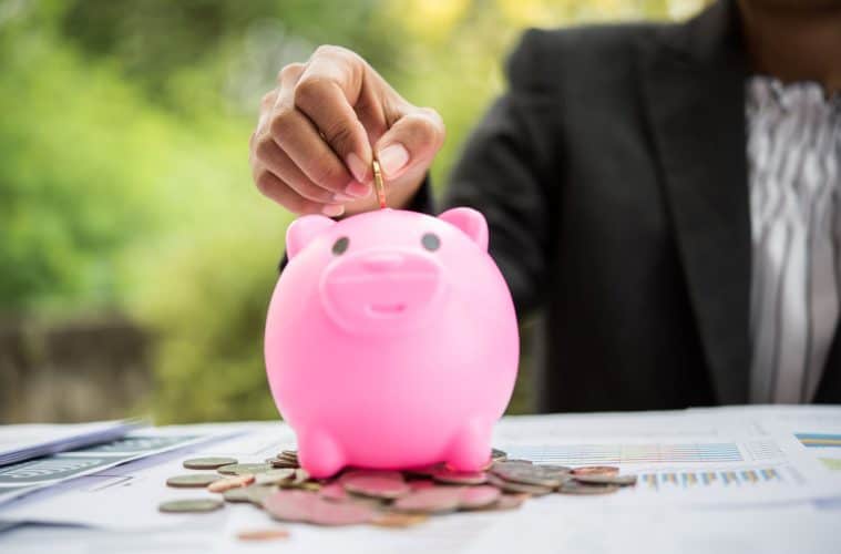 putting coin into a piggy bank on the table finance